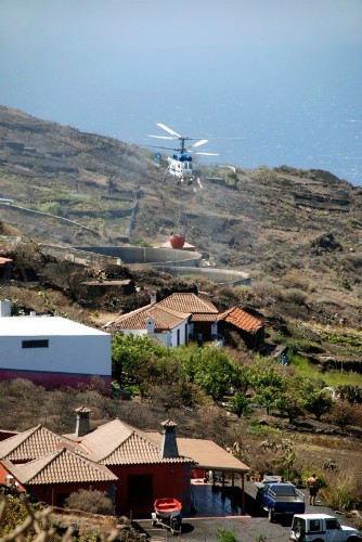 Un helicóptero recarga agua en un estanque para continuar con las labores de extinción del incendio forestal declarado en la madrugada del pasado sábado y que aún hoy sigue sin estar controlado, en la costa de Fuencaliente (La Palma).