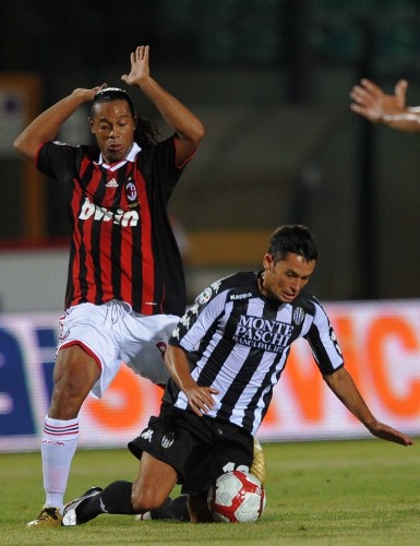 El jugador brasileño del AC Milán Ronaldinho (i) disputa un balón con Codrea (d) del Siena durante el juego de la Serie A que les enfrenta hoy, 22 de agosto de 2009, en el estadio Artemio Franchi de Siena (Italia).