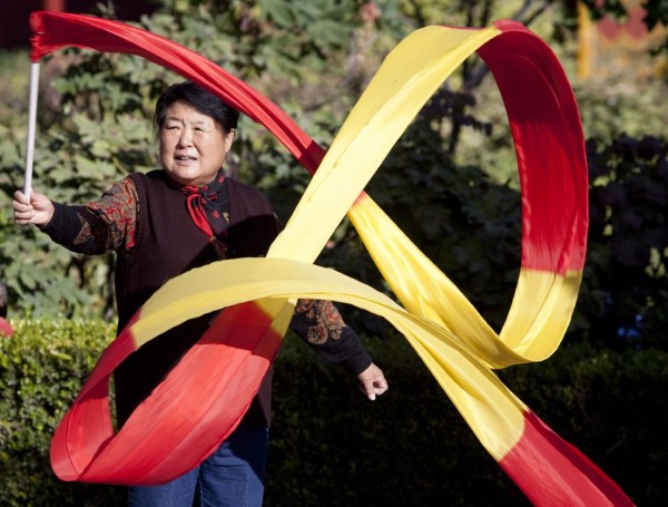 Una jubilada ayuda a expander listones de seda hoy, 19 de octubre de 2009, en un parque de Pekín (China).
