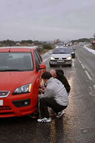 Dos hombres colocan las cadenas a su vehículo en la carretera C-13, en la provincia de Lleida.