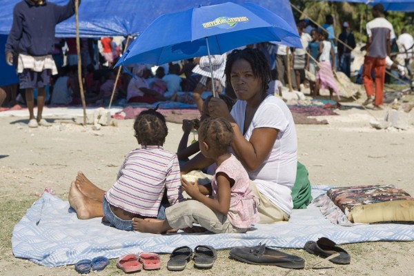 Una madre protege a sus hijos con una sombrilla hoy, en un improvisado campo de refugiados en Puerto Príncipe (Haití).