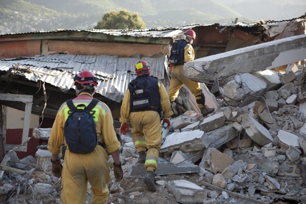 Tres hombres del equipo de asistencia polaco camina en medio de los escombros de un edificio en el centro de Puerto Príncipe.
