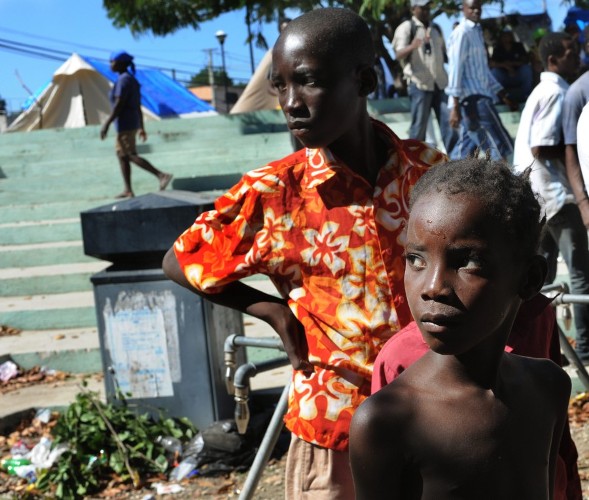 Niños esperan su turno para tomar agua en un campamento de damnificados en Puerto Príncipe.