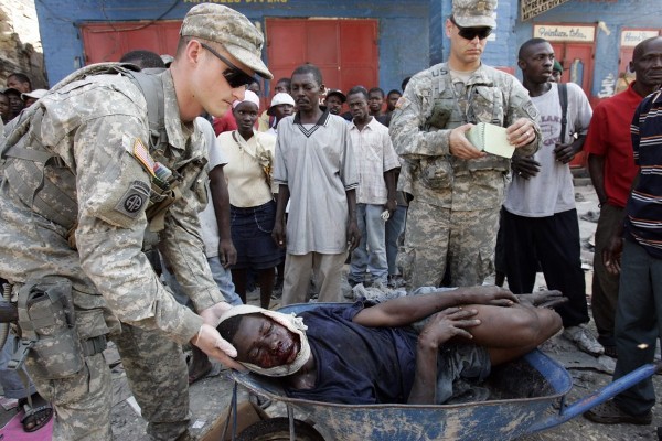Un hombre herido por un disparo de la policía haitiana es revisado por soldados estadounidenses.