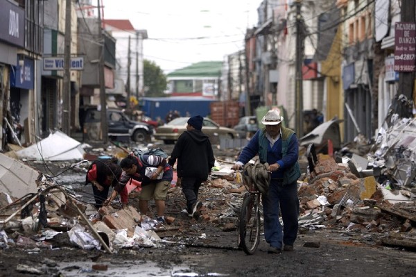 Personas recogen objetos del suelo en una calle de Talcahuano al sur de Santiago.