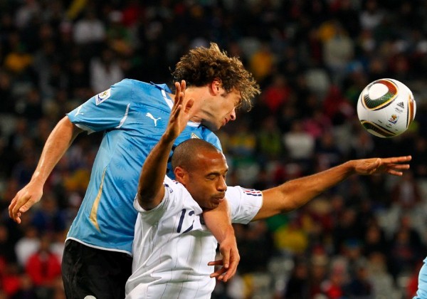 Diego Lugano (i) de Uruguay salta por el balón con Thierry Henry (d) de Francia durante el partido del grupo A, que quedó con empate a cero.