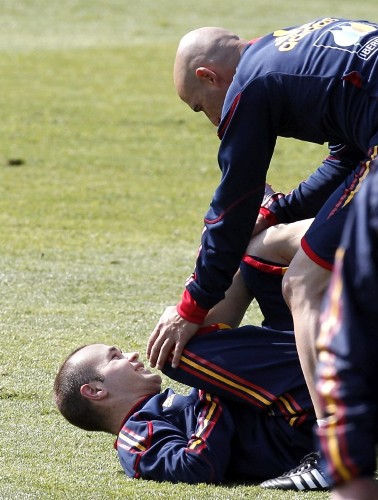 El centrocampista Andrés Iniesta realiza ejercicios con uno de los preparadores físicos.