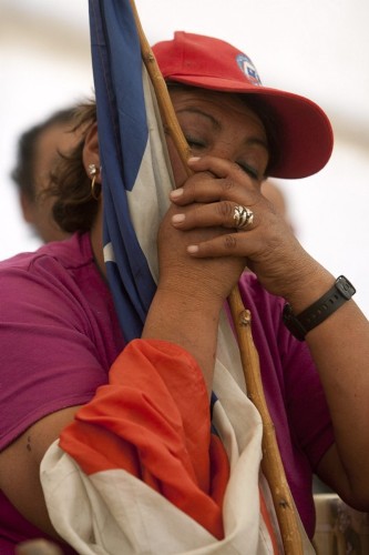 María Segovia, hermana del minero Darío Segovia, abraza una bandera chilena hoy, martes 7 de septiembre de 2010, en la mina San José, cerca a Copiapó (Chile), mientras se trabaja en el rescate de los 33 mineros atrapados 700 metros bajo tierra. La perforadora Schramm T-130, considerada el 'Plan B' para rescatar a los trabajadores, alcanzó en la fecha los 113 metros de excavación, apenas dos días después de su puesta en marcha, informaron fuentes oficiales.