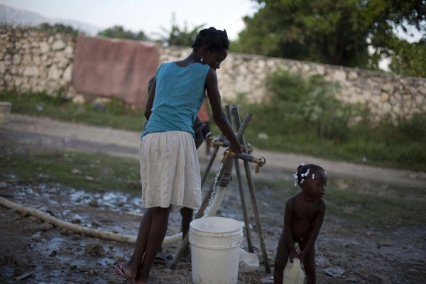 Una mujer llena un cubo con agua en Puerto Príncipe.