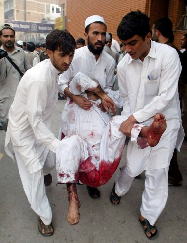 Varias personas trasladan a una de las víctimas de un ataque suicida perpetrado en una mezquita en Peshawar.