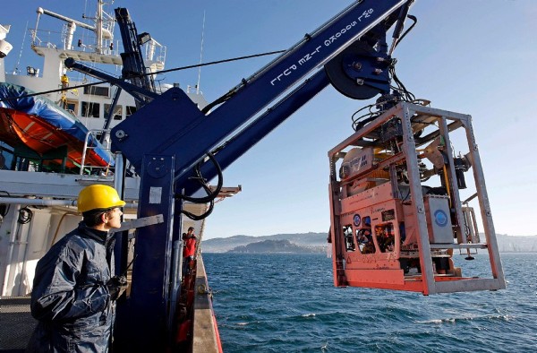 Varios operarios del buque oceanográfico Sarmiento de Gamboa junto al denominado Liropus 2000, un robot no tripulado y manejado a distancia que permitirá la exploración de los ecosistemas marinos hasta una profundidad de 2.000 metros, aunque con capacidad para llegar hasta los 3.000, que hoy ha sido presentado en el puerto de Vigo.