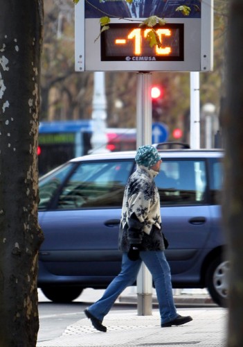 Un hombre camina ante un termómetro de la avenida de la Libertad de San Sebastián que marca un grado bajo cero.