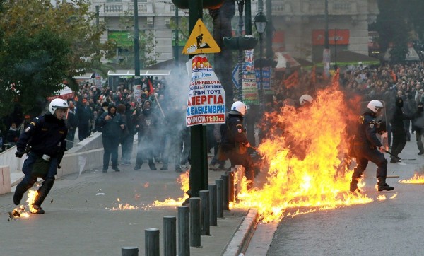 Policías antidisturbios huyen de las llamas de un cóctel molotov.