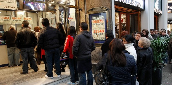Varias personas guardan cola en una céntrica administración madrileña para comprar sus décimos.