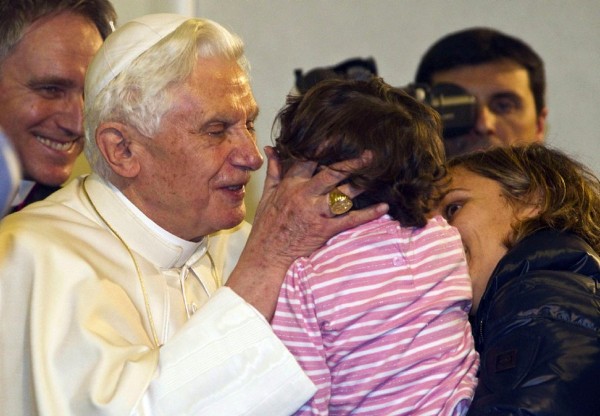 El papa Benedicto XVI saluda a una niña.