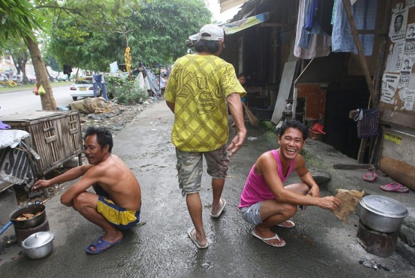 Filipinos preparan su comida en la acera en un distrito urbano pobre de Quezon City.