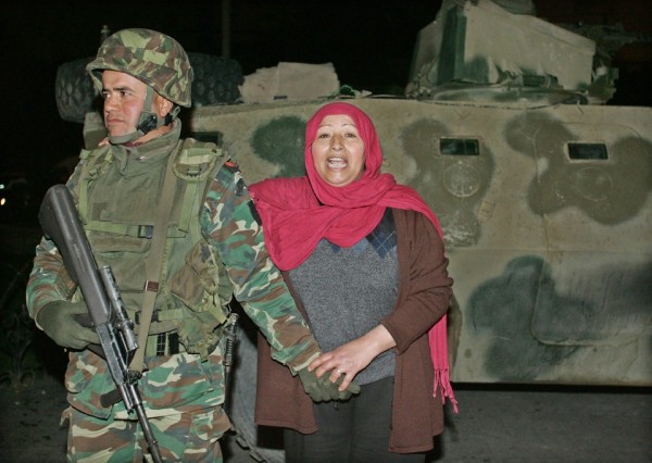 Una mujer toma el brazo de un soldado tunecino.