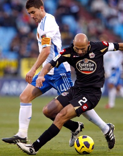 El defensa del Deportivo de La Coruña Manuel Pablo (d) pugna por el balón con el mediocentro del Real Zaragoza Gabi Fernández.