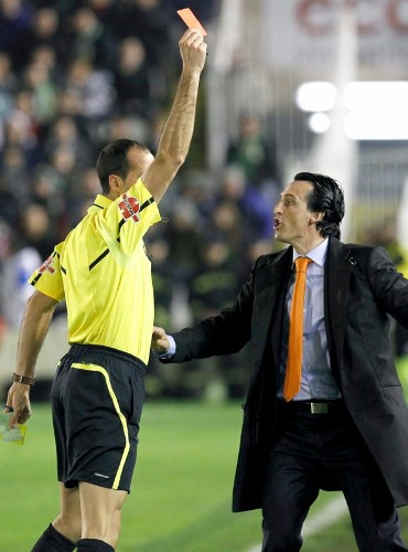 El entrenador del Valencia, Unai Emery (d), intenta impedir que el arbitro Álvarez Izquierdo saque tarjeta roja al central valencianista David Navarro, en el banquillo.