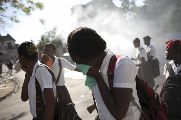 Varoas estudiantes huyen de los gases arrojados por la policía hoy, lunes 7 de febrero de 2011, durante una protesta realizada en las inmediaciones de Champs de Mars, en Puerto Príncipe (Haití). 