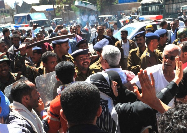 Un grupo de manifestantes antigubernamentales corea consignas delante de varios policías que les bloquean el paso durante una protesta convocada en Saná (Yemen).