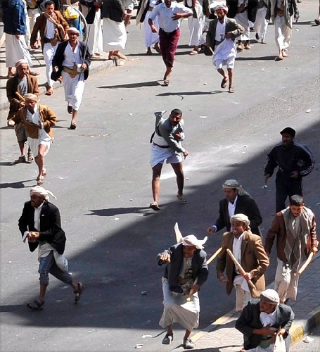 Un grupo de manifestantes pro-gubernamentales armados con palos, arroja piedras a los manifestantes que protestan contra el gobierno, en las calles de Sana, Yemen, ayer viernes.
