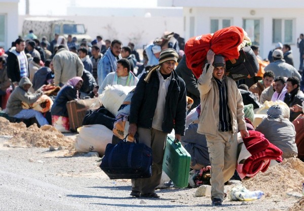 Unos ciudadanos egipcios residentes en Libia cruzan el paso fronterizo de Ras El Jedir, en Túnez.