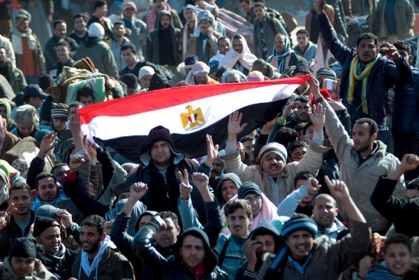 Refugiados egipcios agitan su bandera entre la multitud de refugiados retenidos en la frontera libio-tunecina.