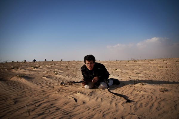 Un soldado rebelde libio busca cubrirse durante un bombardeo de fuerzas gubernamentales en la ruta cerca a Ajdabiya.