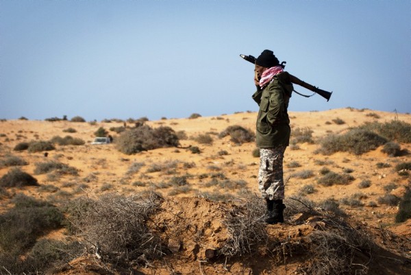 Un rebelde libio permanece armado cerca a un puesto de control en la carretera a Sirte.