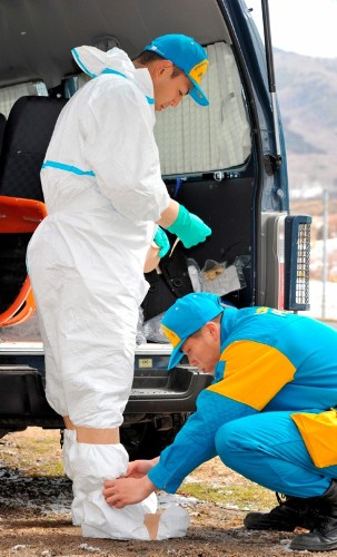 Miembros de la policía japonesa se colocan trajes especiales para protegerse de la radiación antes de entrar a una zona restringida cercana a la central de Fukushima.