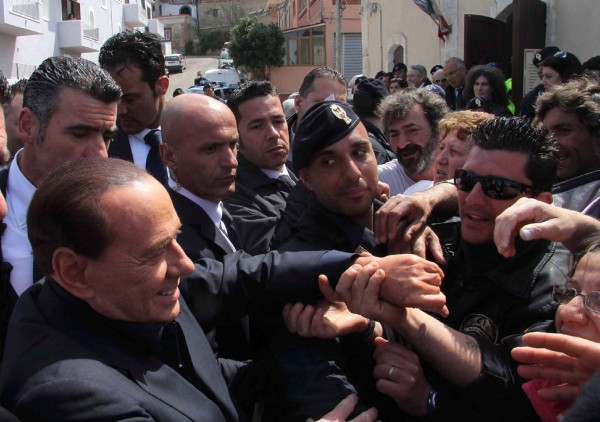 El primer ministro italiano, Silvio Berlusconi, (i), saluda a un grupo de ciudadanos a su llegada al sur de la isla de Lampedusa.