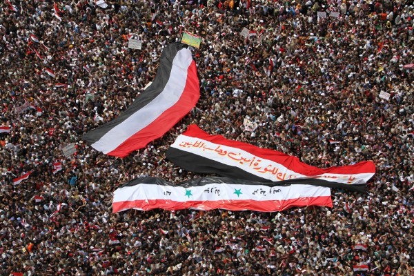 Egipcios despliegan dos grandes banderas de Egipto (i y d) y una de Siria (abajo) durante una manifestación.