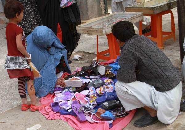 Una mujer afgana ataviada con el tradicional burka escoge un par de zapatos.