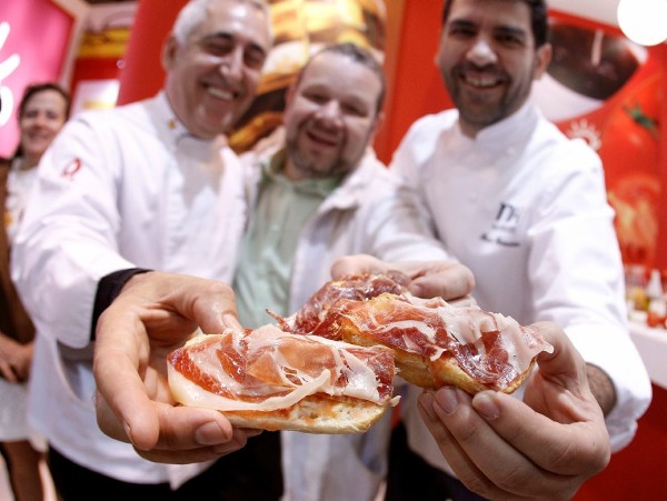 (De izda a dcha.) Los cocineros Adolfo Muñoz, Alberto Chicote y Paco Roncero, muestran un pan con jamón, promocionando el desayuno español, durante la inauguración del XXV Salón Internacional del Club Gourmets de Madrid.