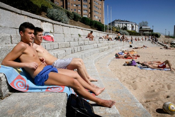 Varias personas disfrutan del sol en la playa.