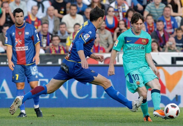 El delantero argentino del F. C. Barcelona, Leo Messi, golpe el balón ante el defensa del Levante, Nano, durante el encuentro correspondiente a la vigésimo sexta jornada de primera división, que ambos equipos disputan esta tarde en el estadio Ciutat de Valencia.