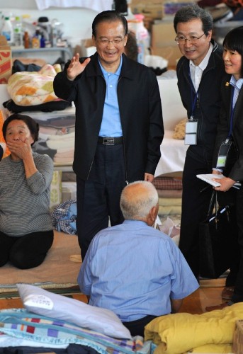 El primer ministro chino Wen Jiabao (c) conversa con algunos de los japoneses acogidos en un centro de ayuda para los supervivientes del tsunami de Japón.