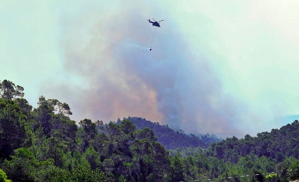 Un helicóptero de lucha contra el fuego descarga sobre el incendio declarado ayer en la sierra de Morna en Ibiza ha quemado ya unas 1.500 hectáreas de pinar, aunque no ha causado heridos ni ha afectado a ninguna vivienda.