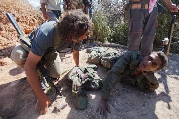Un rebelde (i) interroga a un soldado leal al líder libio Muamar al Gadafi.