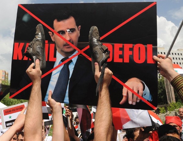 Manifestantes turcos y sirios malean una pancarta del presidente sirio, Bachar al Asad.