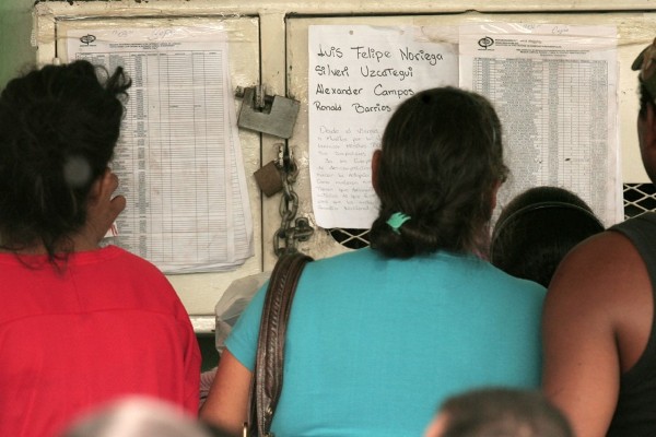 Un grupo de personas observa una lista de reclusos.
