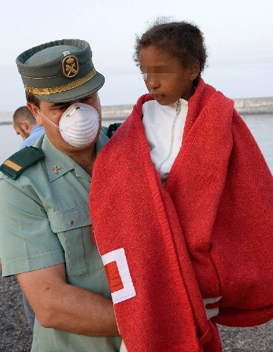 Una niña en brazos de un agente de la Guardia Civil que forma parte de los 54 inmigrantes subsaharianos que Salvamento Marítimo rescató de una balsa neumática semihundida a unas 50 millas al sur de Motril (Granada).