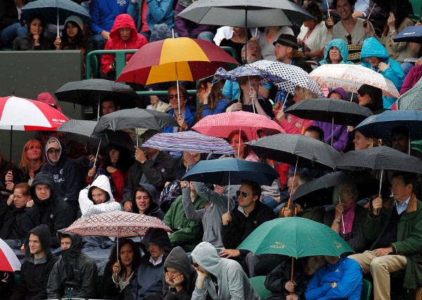 Los espectadores se protegen con paraguas.