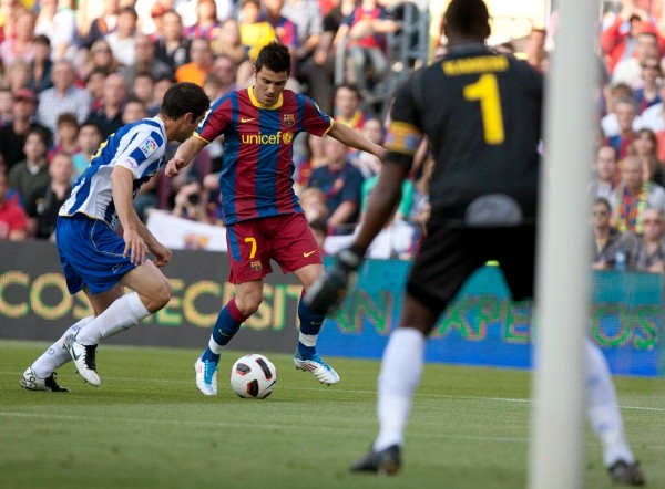 El delantero del FC Barcelona David Villa (c) controla el balón ante la mirada de los jugadores del RCD Espanyol Jordi Amat (i) y el portero camerunés Carlos Kameni.