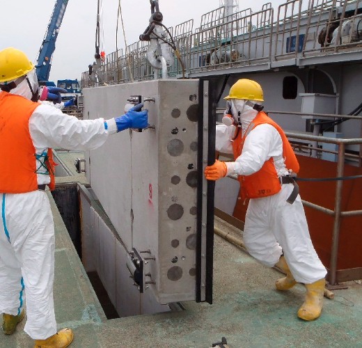 Operarios instalando una plancha de cemento para reducir la contaminación radioactiva en el mar, en la central de energía atómica de Fukushima. 