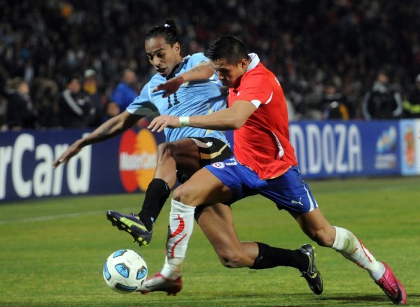 El jugador de la selección de Uruguay de fútbol Álvaro González (izq) disputa el balón ante Alexis Sánchez de la selección de Chile (der).