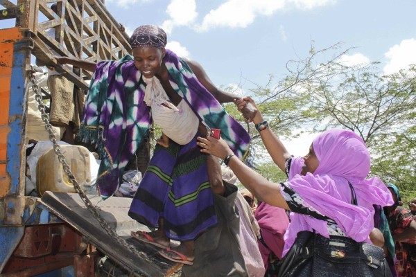Una mujer somalí es ayudada al bajar de un camión a su llegada al campo de refugiados de Mogadiscio, Somalia.