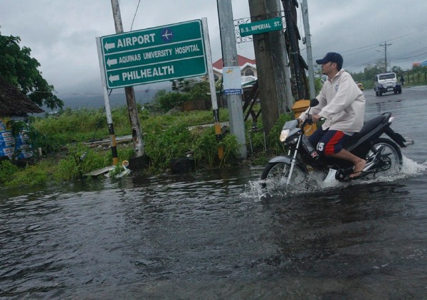 Un motorista filipino circula bajo la intensa lluvia por una calle inundada en la ciudad de Legazpi, en la provincia oriental filipina de Albay.