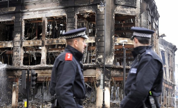 Bomberos apagan los últimos rescoldos de de los edificios quemados durante los graves disturbios.